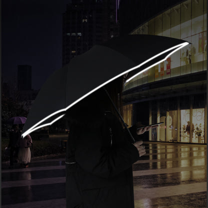 Person holding a glowing umbrella in front of a building at night